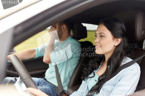 Image of woman driving car and man covering face with palm