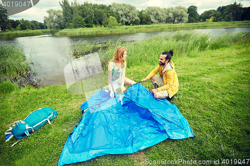 Image of happy couple setting up tent outdoors