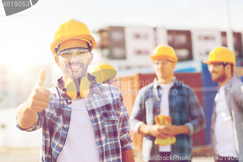 Image of group of smiling builders in hardhats outdoors