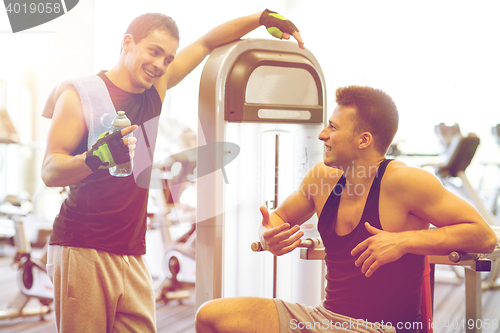 Image of smiling men exercising on gym machine