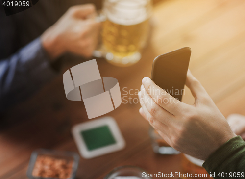 Image of close up of friends with smartphone and beer