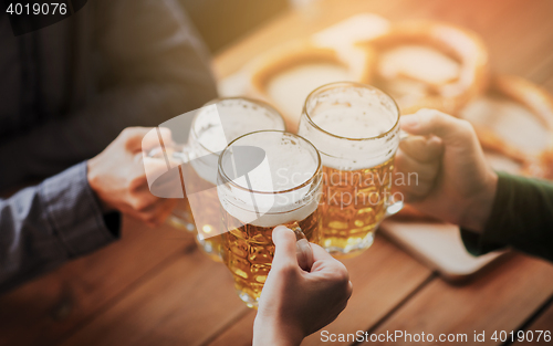 Image of close up of hands with beer mugs at bar or pub