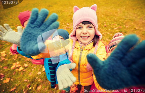 Image of happy children waving hands in autumn park