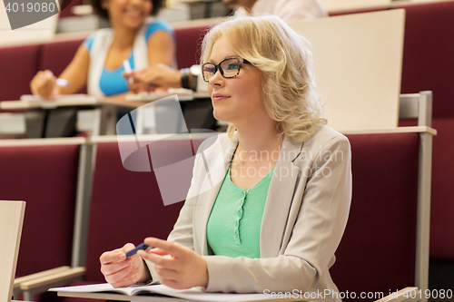 Image of student girl writing to notebook in lecture hall