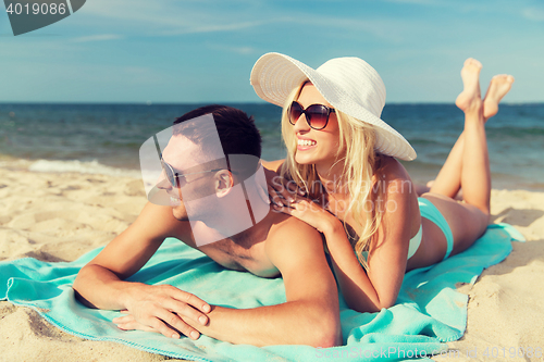 Image of happy couple in swimwear lying on summer beach