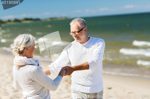 Image of happy senior couple holding hands on summer beach