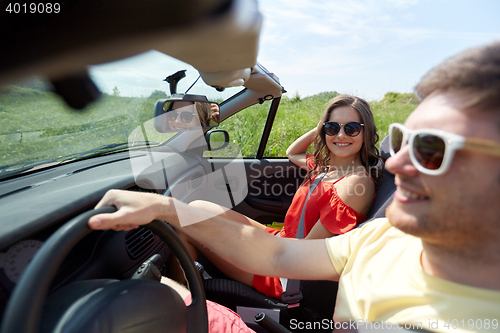 Image of happy couple driving in cabriolet car at country