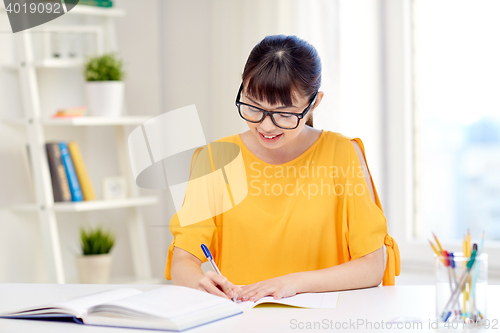 Image of happy asian young woman student learning at home