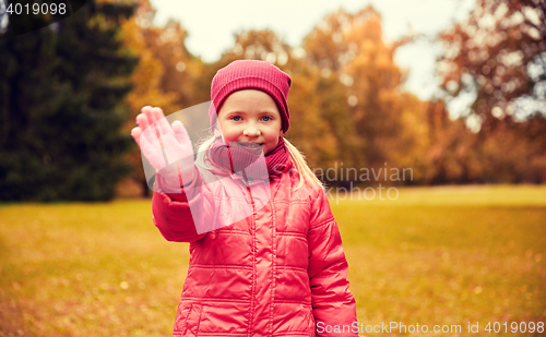 Image of happy little girl waving hand in autumn park