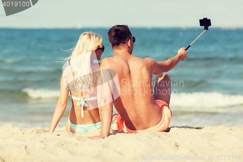 Image of happy couple in swimwear sitting on summer beach