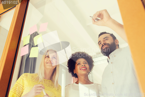 Image of happy creative team writing on stickers at office