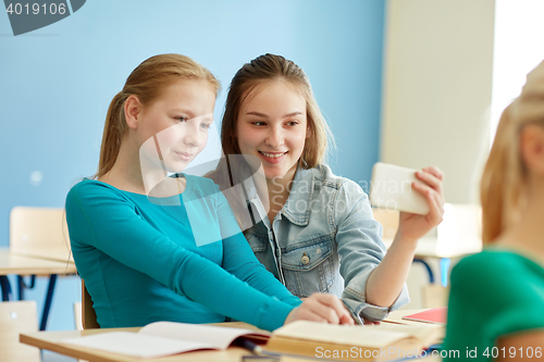 Image of student girls taking smartphone selfie at school