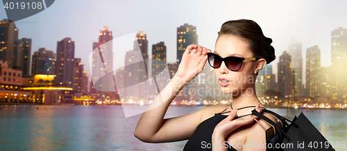 Image of happy woman in black sunglasses with shopping bags