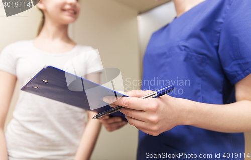 Image of close up of nurse with clipboard and pen with girl