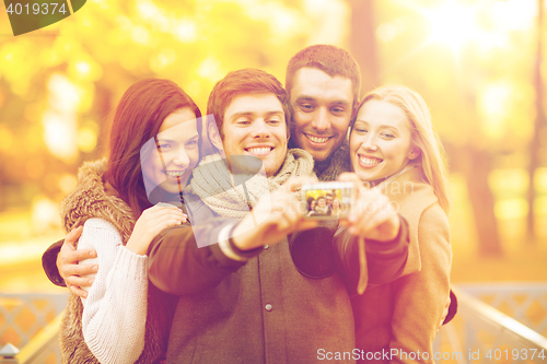 Image of group of friends with photo camera in autumn park