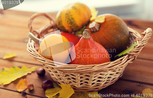 Image of close up of pumpkins in basket on wooden table