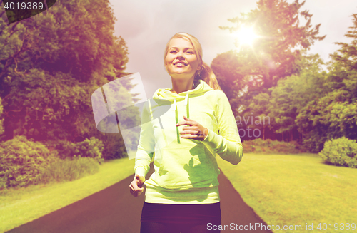 Image of happy smiling young woman jogging outdoors