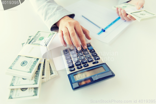 Image of close up of hands counting money with calculator