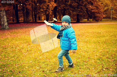 Image of happy little boy playing with toy plane outdoors