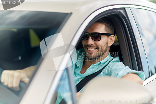 Image of happy smiling man in sunglasses driving car