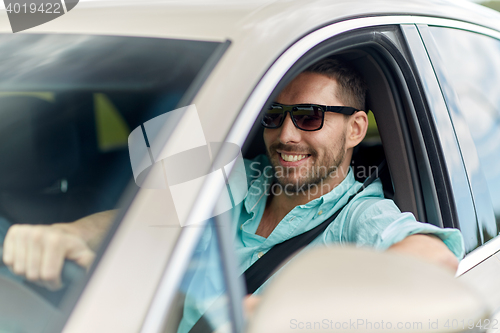 Image of happy smiling man in sunglasses driving car