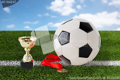 Image of close up of football ball, golden cup and medal