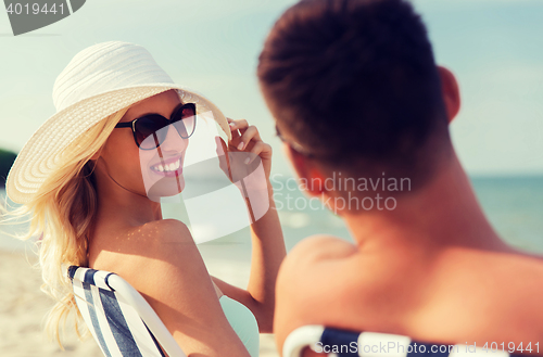 Image of happy couple sunbathing on summer beach