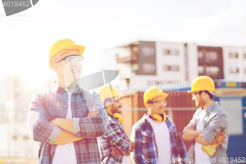 Image of group of smiling builders in hardhats outdoors