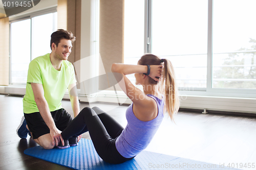 Image of woman with personal trainer doing sit ups in gym