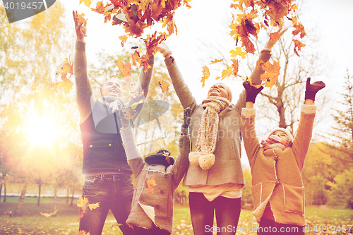 Image of happy family playing with autumn leaves in park