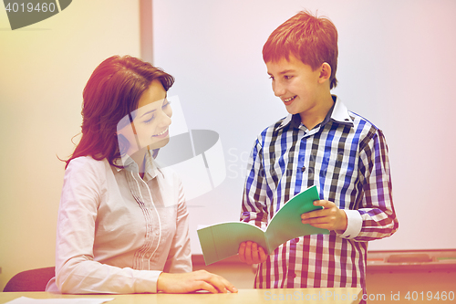 Image of school boy with notebook and teacher in classroom