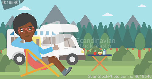 Image of Woman sitting in chair in front of camper van.