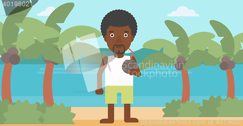 Image of Man drinking coconut cocktail on the beach.