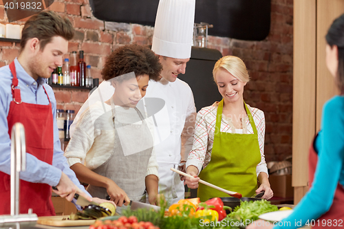 Image of happy friends and chef cook cooking in kitchen