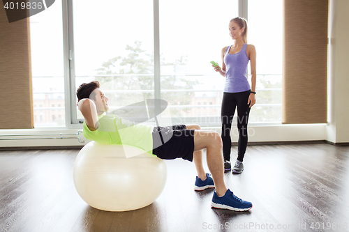 Image of smiling man and woman with exercise ball in gym