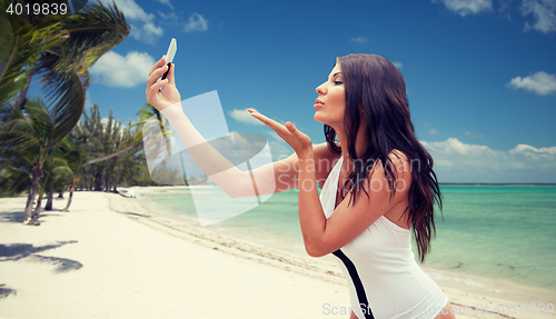 Image of young woman taking selfie with smartphone