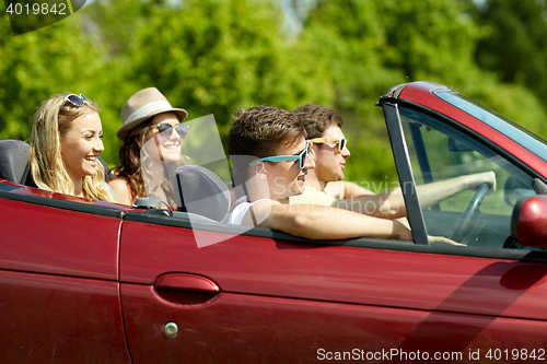 Image of happy friends driving in cabriolet car