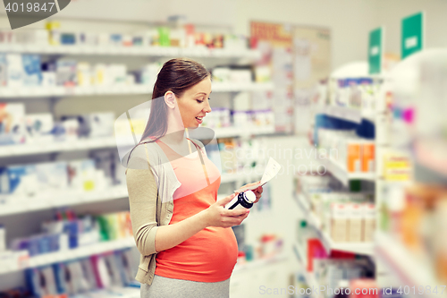 Image of happy pregnant woman with medication at pharmacy
