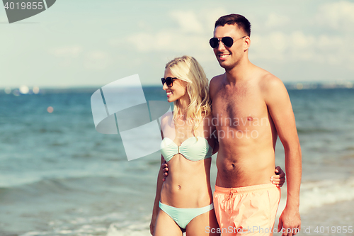 Image of happy couple in swimwear walking on summer beach