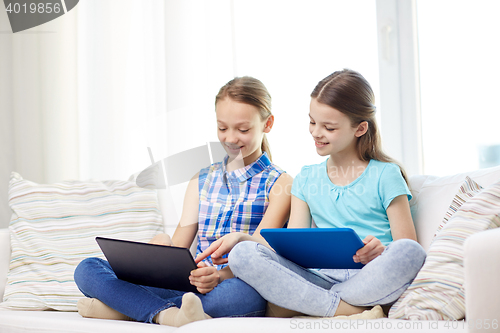 Image of happy girls with tablet pc sitting on sofa at home