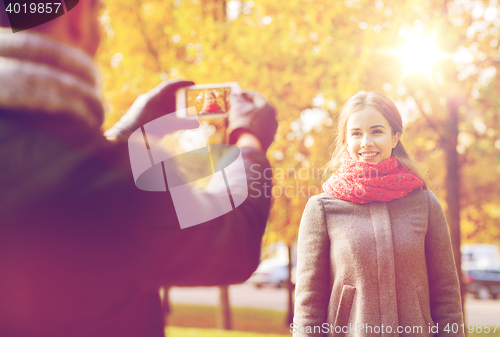 Image of smiling couple with smartphone in autumn park