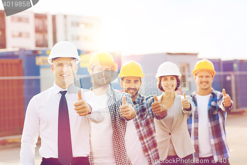 Image of group of smiling builders in hardhats outdoors