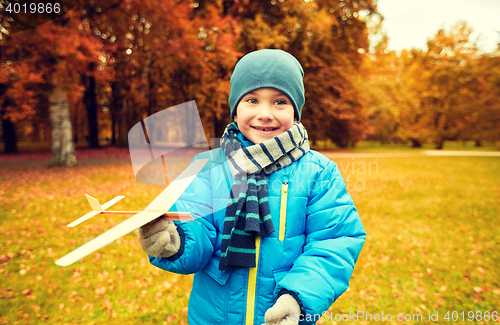 Image of happy little boy playing with toy plane outdoors