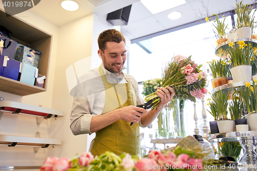 Image of smiling florist man making bunch at flower shop