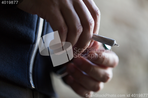 Image of close up of addict hands with marijuana joint tube