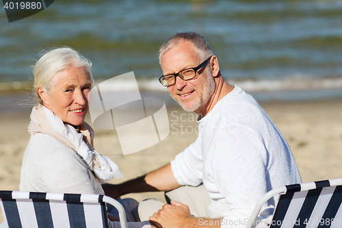 Image of senior couple sitting on chairs at summer beach