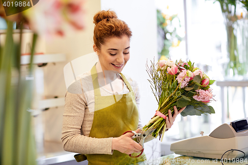 Image of smiling florist woman making bunch at flower shop