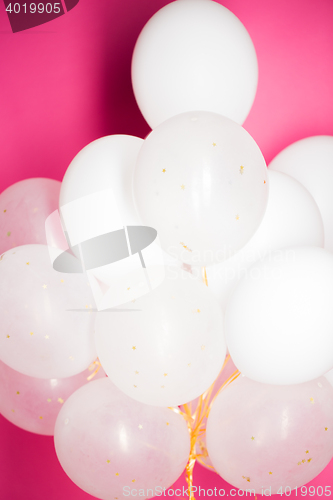 Image of close up of white helium balloons over pink