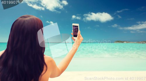 Image of young woman taking selfie with smartphone