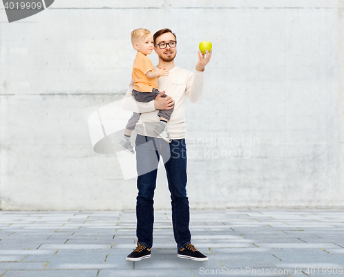 Image of happy father and little son with green apple